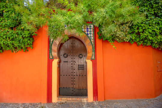 Fototapeta Architectural landscape with colorful wall and wooden stylish door in old district Albaicin. Granada, Andalusia, Spain