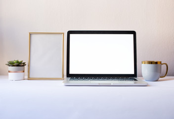 Laptop computer with blank screen with blank frame, gray mug and succulent in office on the white background with mockup frame and cup. Mock up screen in notebook. White office. Minimalism concept