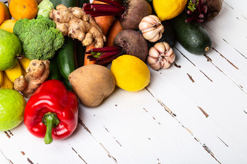 Variety of fresh raw natural colorful vegetables and fruits on old rustic white background.