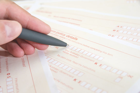 pen in hand fills Australian tax forms. Close-up. Images are toned. Business concept.