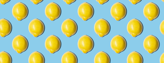 Seamless pattern of fresh lemons on blue background. Food texture