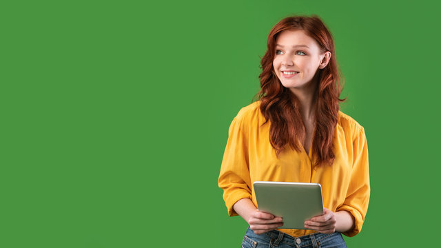 Smiling Girl Holding Digital Tablet Looking Aside On Green Background - Powered by Adobe