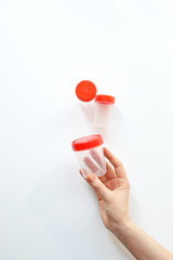 Sterile transparent empty plastic container for analysis in the hands. Open and closed containers. Red lid Sterile medical container for biomaterial. Isolated on white