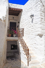 Fototapeta premium One of the charms of Mykonos, Greek island in the heart of the cyclades, are its narrow streets : white houses with small flowered balconies touching almost above paved streets