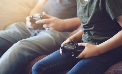 Hands Holding video game or game console. Child boy and Father playing game online stay at home...