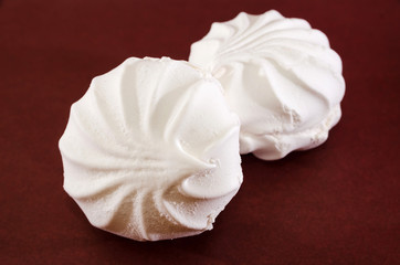 two white marshmallows on a brown background. Close-up.