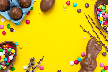 Colorful Easter BAckground. Chocolate Eggs and Candy on Yellow Background. Copy Space on Flat Lay Design