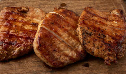 fried juicy pork steak on a wooden board, grilled meat