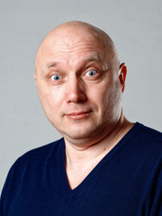Obraz premium Portrait of a bald cheerful man on a gray background