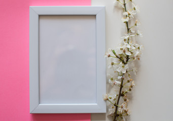 White blank frame on pink background with flower. Minimalistism background. Mock up frame. Summer or travel concept. Copy space