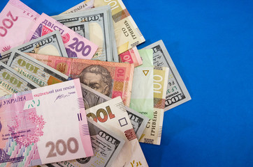 different hryvnias and dollars on a blue background. Copy space.