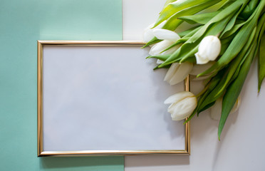 Gold blank frame on pastel green background with tulip flower. Minimalistism background. Mock up frame. Summer or travel concept. Copy space