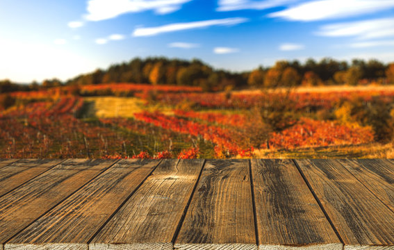 Empty wooden table and blurred autumn vineyards background. Natural template with beauty bokeh and warm sunlight. Concept banner for products display