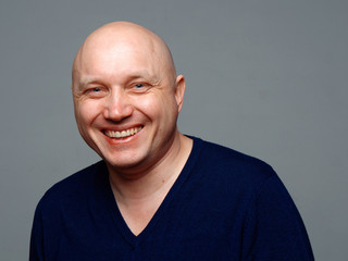 Portrait of a bald cheerful man on a gray background