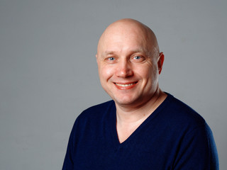 Portrait of a bald cheerful man on a gray background