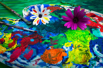 une palette de peinture avec deux fleurs , dont une blanche aux pétales peinte