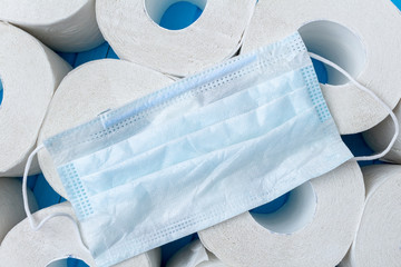 lots of toilet paper rolls and medical protective mask background close up. Isolation, quarantine...