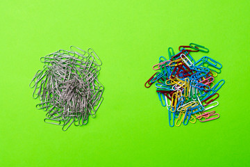 two heaps of metal and colored paper clips on a green background. place for text
