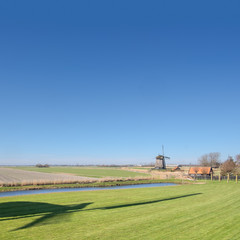 Windmill in a polder landscape with the shadow of another windmill in the foreground