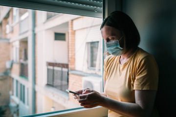 Woman in self-isolation during virus outbreak using mobile phone