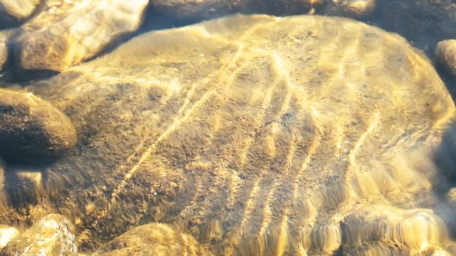 Play of Sun light on the stones under water, shot at Murti river, Dooars, West Bengal, India. Abstract nature footage.