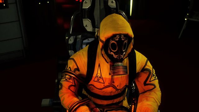 A medic in protective chemical clothing is working at a computer. A man in a yellow bacteriological protective suit and gas mask.