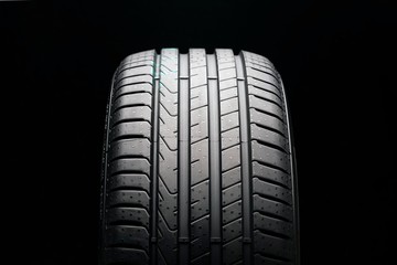 new summer tire on a black background, front view