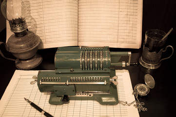 An old mechanical calculator, an arithmetic counter, accounting journals, a kerosene lamp, and a...