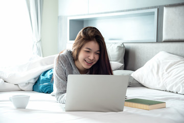 Business asian woman working with laptop at home,private business online lying on bed in bedroom chat and shopping on line.