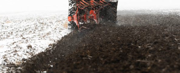 Tractor plowing a field in the snow