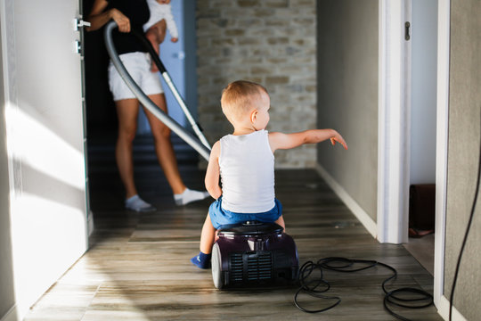 Mom with children vacuums the floor, stay home