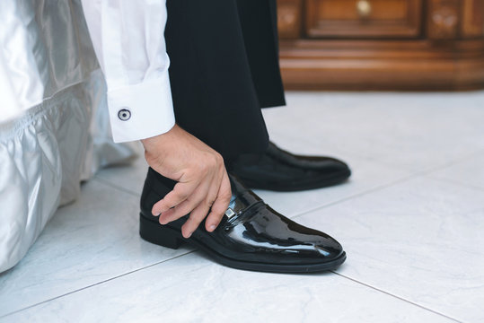 man putting on black shoe