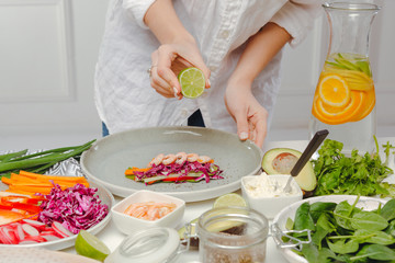 Woman's hands adding lime juice to spring roll. Photo recipie of asian dish. Healthy and tasty food.
