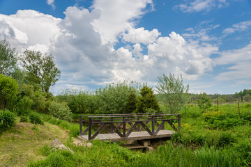 Wooden bridge over a stream on background of blue sky