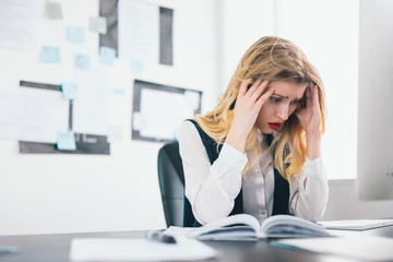 young blond beautiful woman manager works in her modern office, holding pen in her hand looks helpless and desperate facing deadline, multitasking, work concept