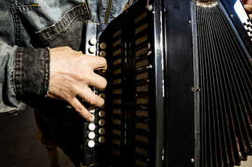 Male fingers on the keys of an old worn-out accordion.