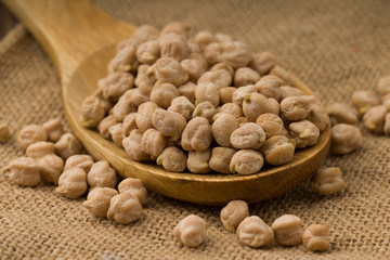 chickpeas over wooden spoon on sackcloth background. Close up