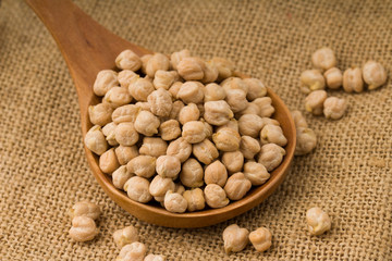 chickpeas over wooden spoon on sackcloth background
