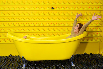 Frau im Abendkleid freut sich in gelber Badewanne