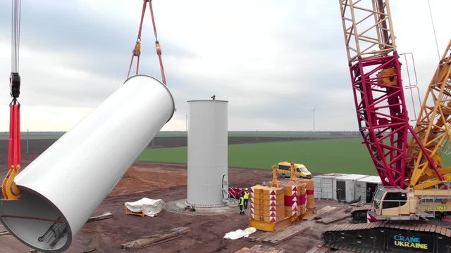 Building process of wind energy power tower mill, under construction. Installation tower, workers inside assembling the pillar of windmill. Green, clean, renewable energy. Aerial footage.