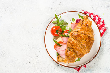 Croissant sandwich on white table.