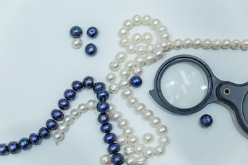 magnifier and pearl necklace closeup on a white background