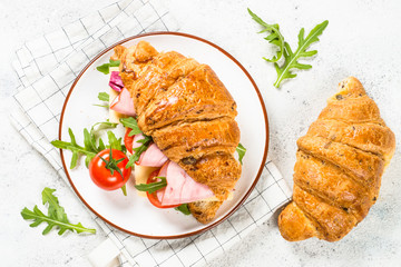 Croissant sandwich on white table.