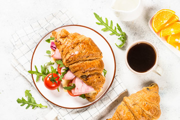 Croissant sandwich on white table.