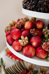 different kinds of fresh fruit on a tray on a banquet. fruit background with peaches, grapes and figs. selective focus