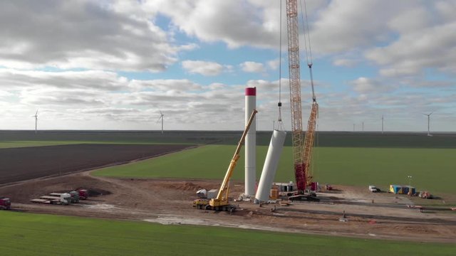 Building process of wind energy power tower mill, under construction. Installation tower, workers inside assembling the pillar of windmill. Green, clean, renewable energy. Aerial footage.