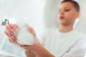 Fototapeta premium Cute boy washing his hands in bathroom. Protection against viruses and bacteria.
