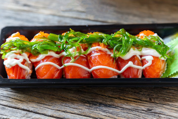 Salmon Sushi on a black plate on a wooden table
