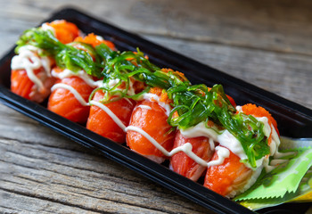 Salmon Sushi on a black plate on a wooden table