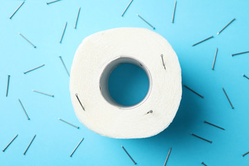 Toilet paper and nails on blue background, top view